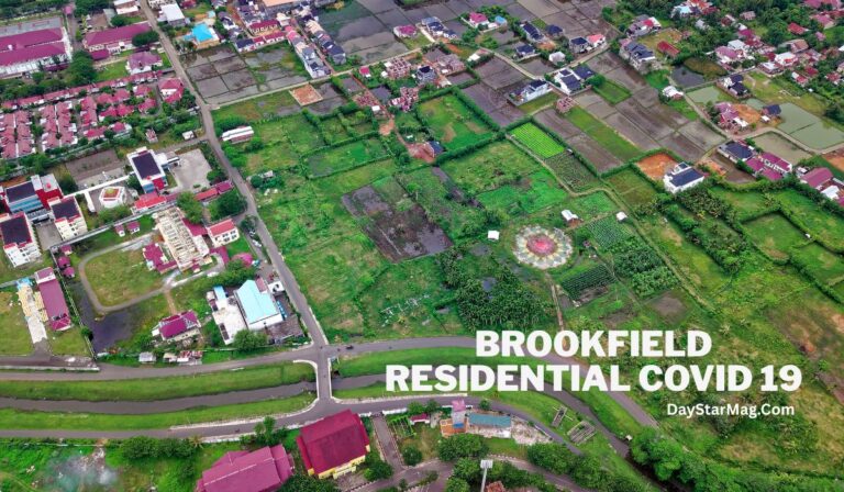 An aerial view of a residential and agricultural area with green fields, houses, and roads. The image shows a mix of developed and undeveloped land, with buildings featuring red and blue roofs. Text on the image reads “BROOKFIELD RESIDENTIAL COVID 19” and “DayStarMag.Com.”