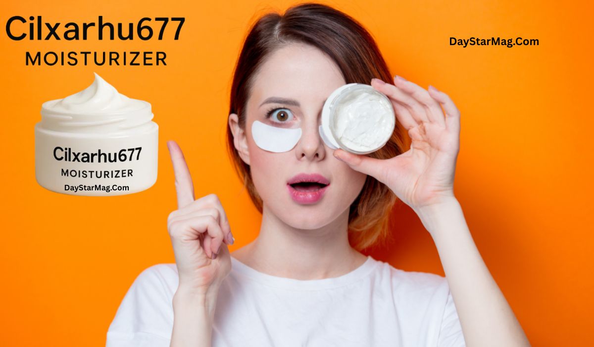 A surprised young woman with fair skin and short hair holds an open jar of white cream near her eye while wearing an under-eye patch. She points upward with her other hand. The background is bright orange, and there is text on the image that reads “Cilxarhu677 Moisturizer” and “DayStarMag.com.”