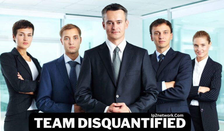 A group of five business professionals dressed in formal suits stand confidently in an office setting with glass walls. The man in the center is standing slightly forward with his hands clasped. Text on the image reads “TEAM DISQUANTIFIED” and “daystarmag.Com.”